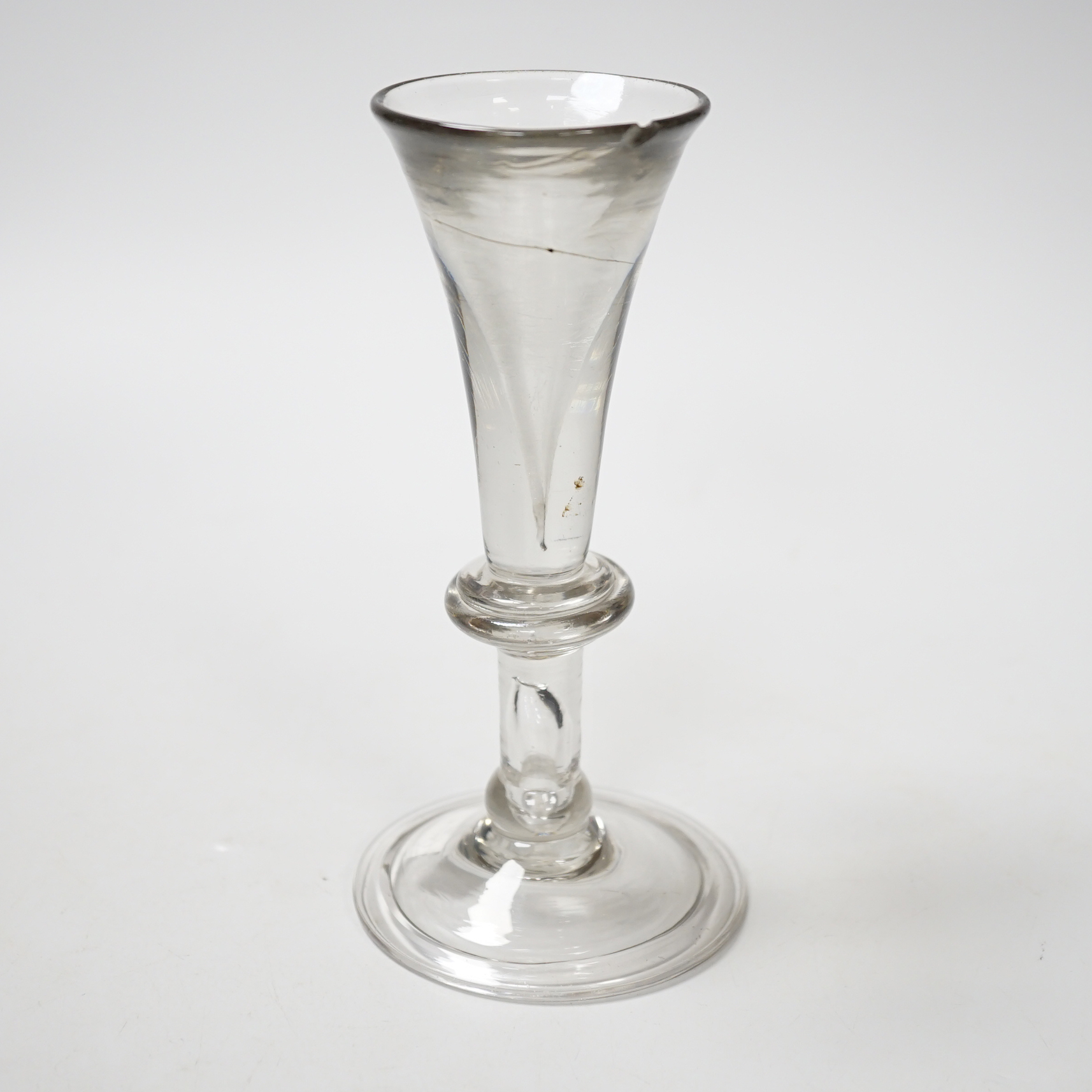 An English lead crystal baluster toastmaster’s glass, c.1710-20, elongated trumpet deceptive bowl on triple flattened annular knop, plain teared section includes a basal knop, conical folded foot, 15cm high